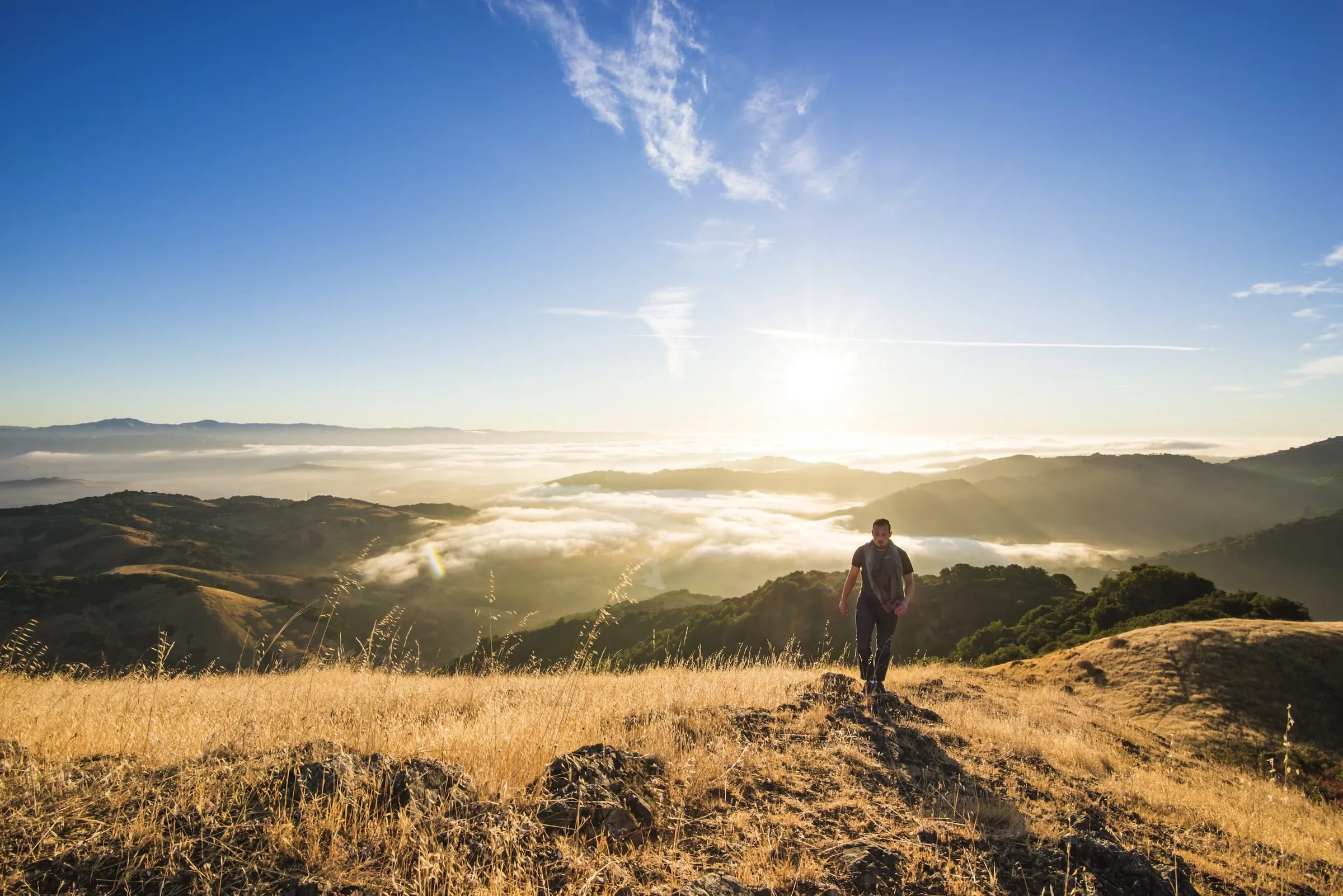 A hiker on a ridge above the clouds at sunrise