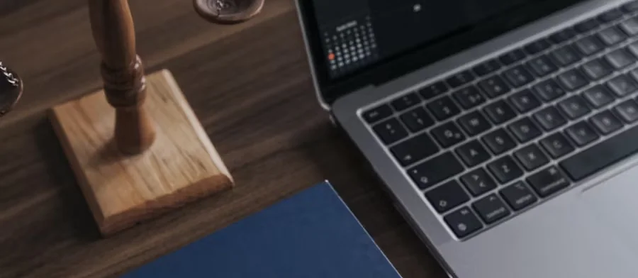 A laptop and a gavel on a timber desk